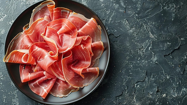 Photo slices of prosciutto di parma or jamon serrano iberico on a black plate