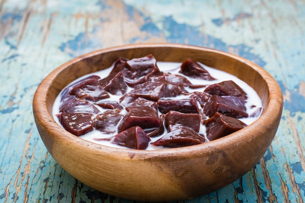 Slices of raw beef liver soaked in milk in a wooden bowl on the table