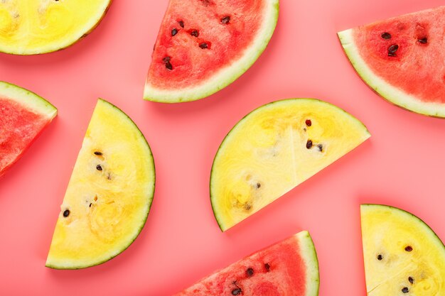 Slices of red and yellow watermelon on pink 