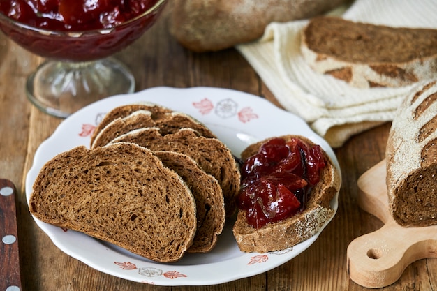 Slices of rye bread with plum jam on a wooden table