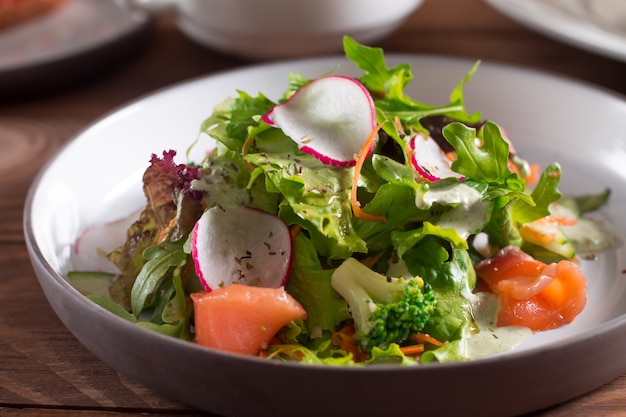 Slices of salmon with fresh vegetable salad on a plate.