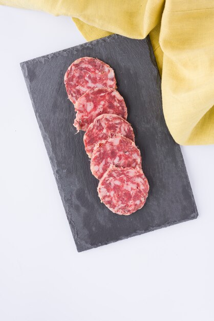 Slices of sausage on slate table and yellow cloth