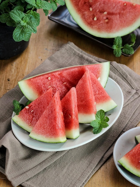 Slices of sweet watermelon on white plate with mint leaves on the wooden table.