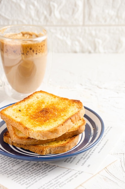 Slices of toasted bread with butter and coffee with milk White background