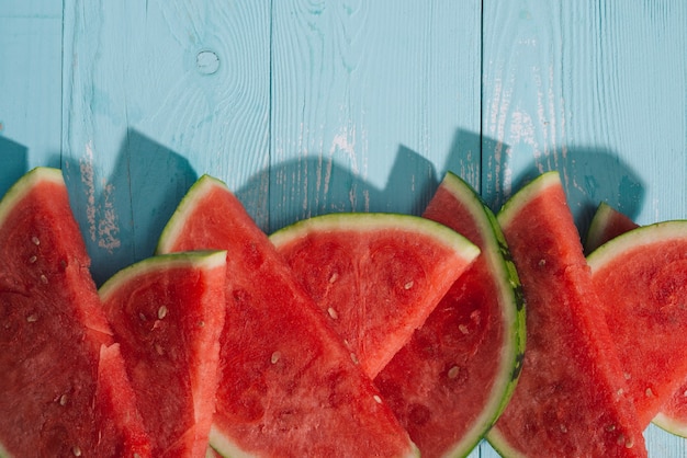 Slices of watermelon on blue wooden desk.