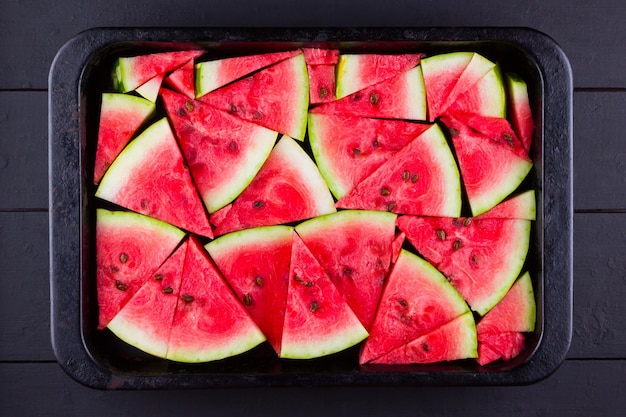 Slices of watermelon on dark boards Sliced watermelon in vintage baking sheet Red watermelon