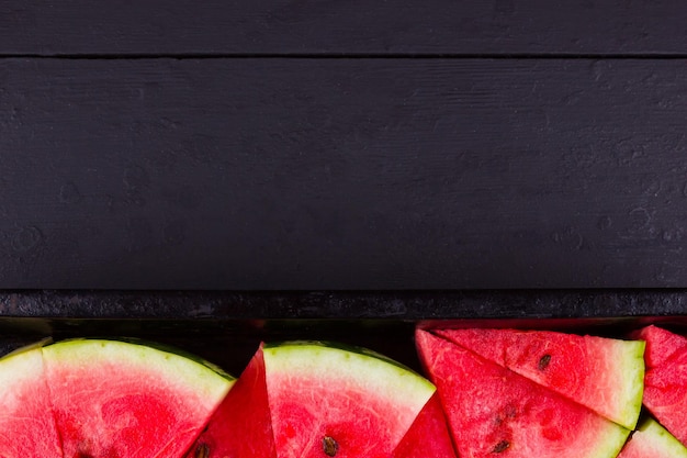 Slices of watermelon on dark boards Sliced watermelon in vintage baking sheet