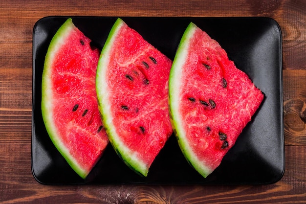 Slices of watermelon on a plate on a wooden background