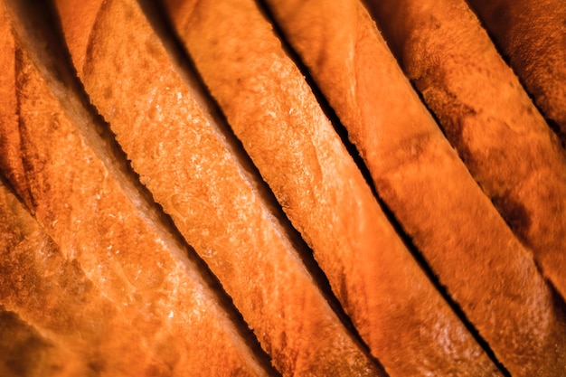 Slices of white bread close up as a background backdrop of rough textured surface chopped pieces loaf of natural organic food top view