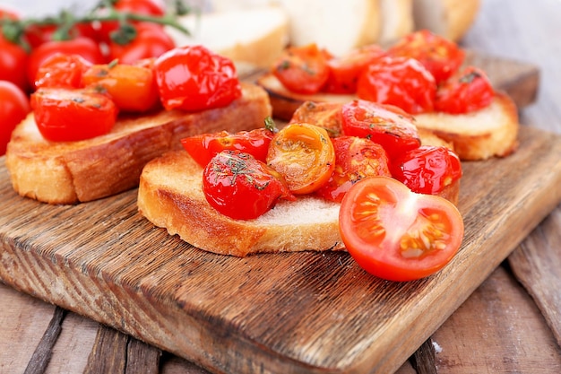 Slices of white toasted bread with canned tomatoes on cutting board on wooden table closeup