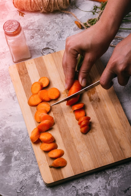 Slicing carrots with female hands with a knife