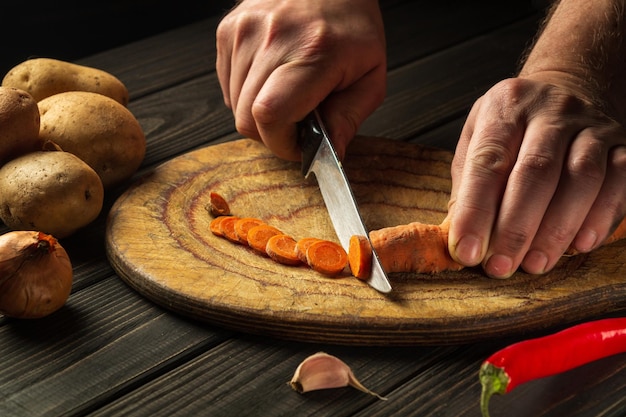 Slicing carrots on a wooden board for cooking