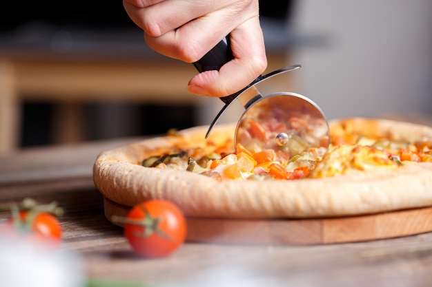 Slicing fresh pizza with roller knife