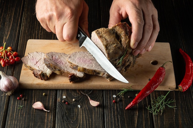 Slicing juicy beef steak with a knife in the hands of a chef closeup The concept of cooking