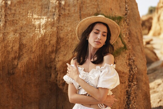 Slim attractive young woman posing against sand rocks