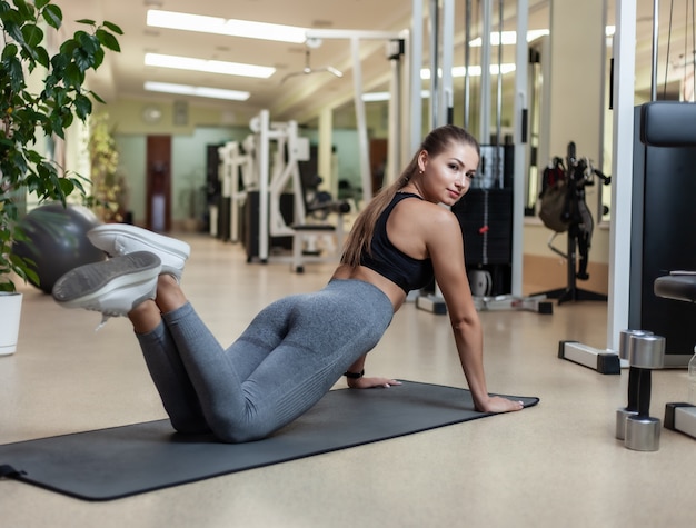 Slim fit woman in sportswear getting ready doing push-ups from the floor in the gym. Healthy lifestyle concept