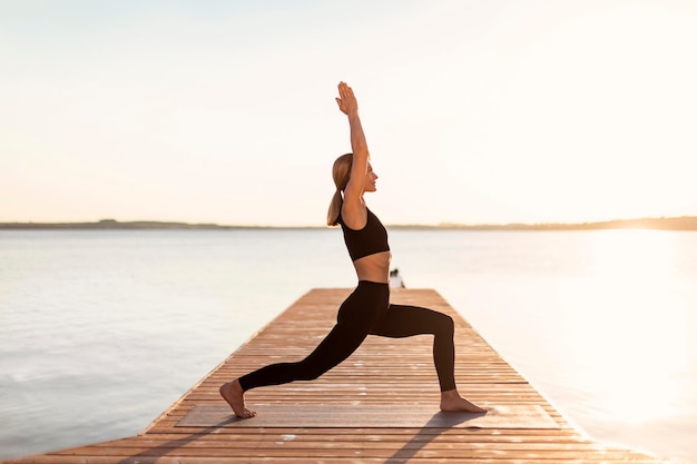 Slim Middle Aged Woman Practicing Yoga Outdoors Making Warrior 1 Pose