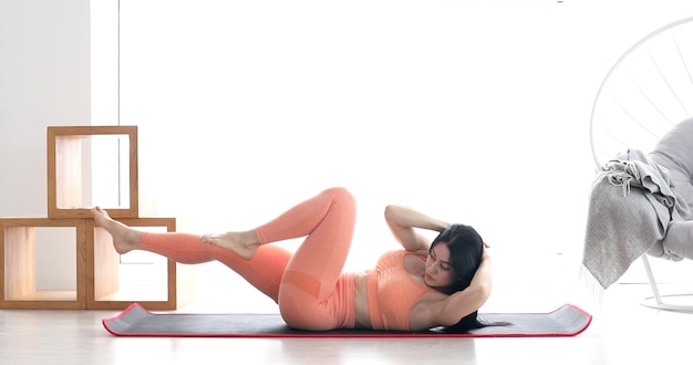 Slim sporty girl doing v-ups abs workout at home.