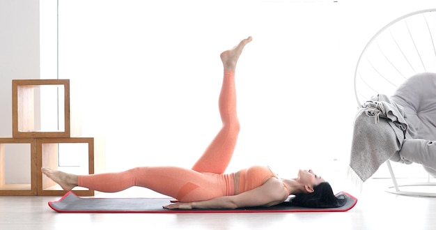 Slim sporty girl doing v-ups abs workout at home.