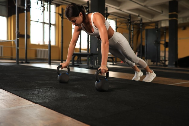 Slim sporty woman doing pushups in a gym Crossfit training