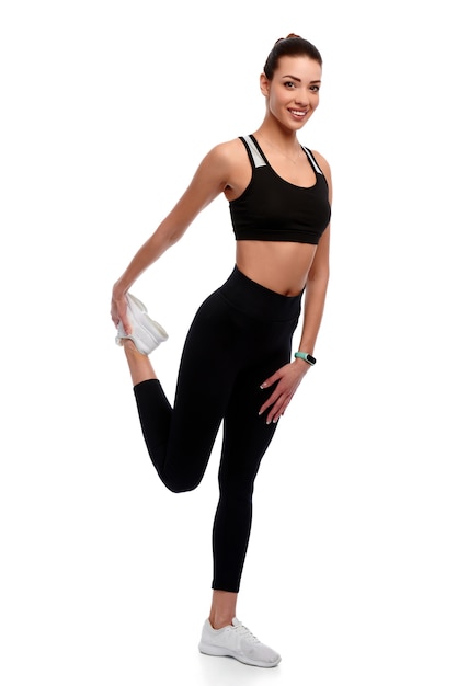 Slim strong athletic woman in sport wear doing stretching exercise in white isolated background