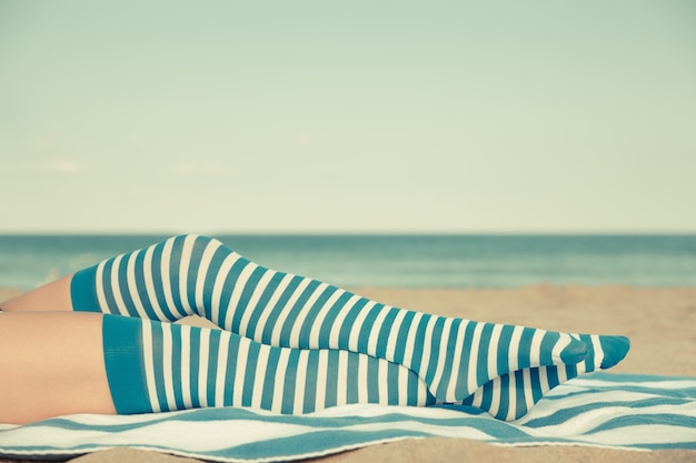 Slim woman legs on a beach. Summer vacation and travel concept. Retro