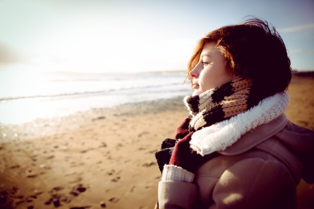 Slim woman looking at the sea during the sunset