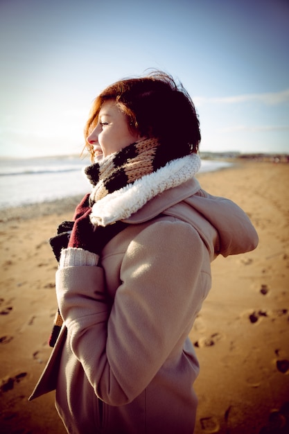 Slim woman looking at the sea during the sunset