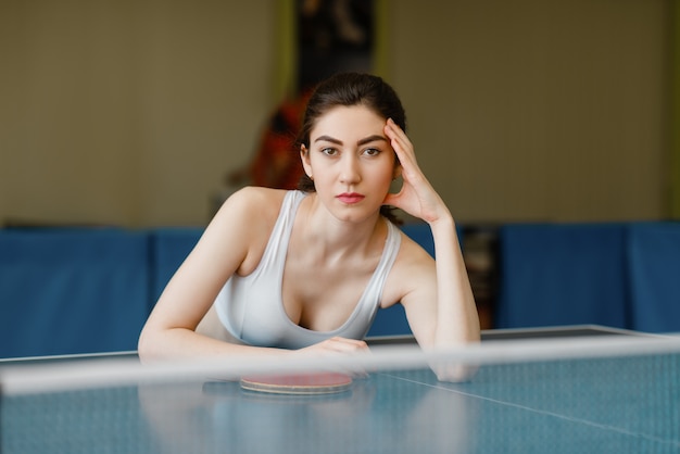 Slim woman poses at the ping pong table indoors