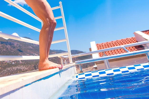 Slim woman in a swimsuit standing on a platform in the pool