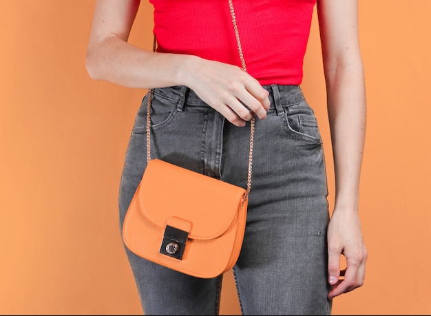 Slim woman with yellow leather bag on orange