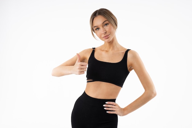 slim young woman in black sportswear with hand gesture