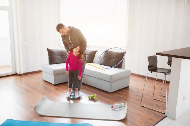 Slimming. Father and daughter are weighed on indoor household scales. Funny and joyful moments having fun in the family. Diet, proper nutrition and healthy lifestyle concept.