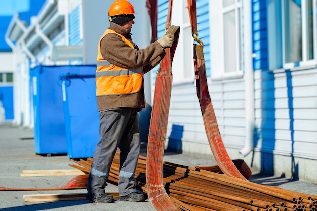 Slinger stacks thin metal pipes in stack on construction site Closeup Real workflow Unloading of materials for construction Production background for equipment supplier