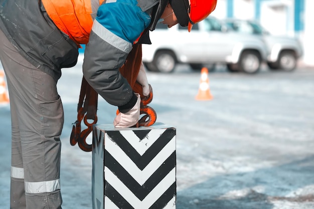 Slinger in work clothes hooks control load with hook Authentic scene work at production base on street of winter day