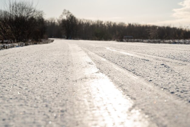 Slippery frozen road on gloomy winter day close up Fast change of weather icy road tire tracks