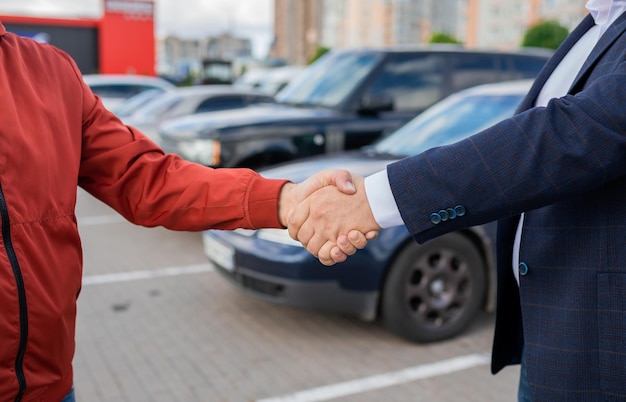 Slose up People shaking hands with each otherxASuccessful car salepurchase transaction