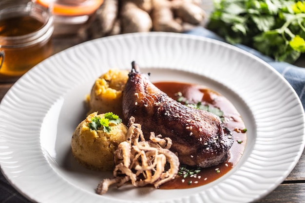 Slow roasted chicken leg on honey and ginger mashed potatoes with onion and coriander Top of view