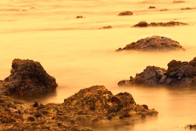 Slow shutter speed photographing water surrounding rock formation in Namibia Africa at sunset in the Atlantic Ocean