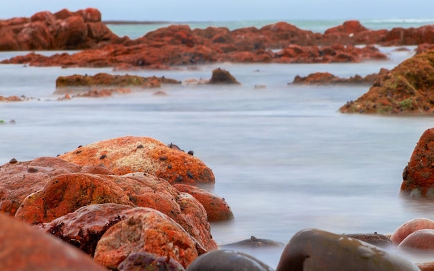 Slow shutter speed photographing water surrounding rock formation in Namibia Africa at sunset in the Atlantic Ocean