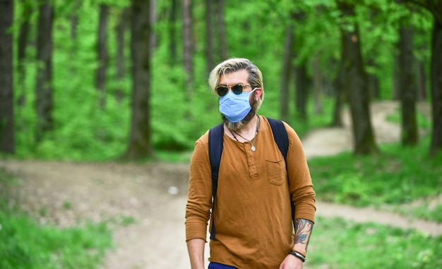 Slowly emerge from lockdown restrictions Walk in park Avoid infection Man enjoy nature wearing face mask Hipster protecting from air contamination or coronavirus Virus infection Stop infection