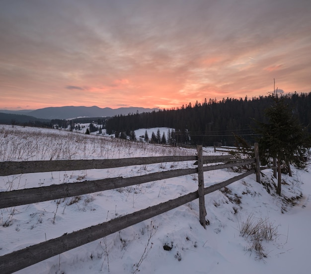 Small alpine village and winter snowy mountains in first sunrise sunlight around Voronenko Carpathian Ukraine