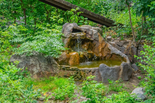 Small artificial waterfall made of granite stones A waterfalls made of artificial rock in the state park Cold mountain water flowing down the rocks in the river on nature outdoors