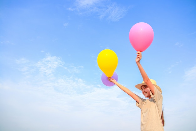 A small Asian woman wearing a hat holding a colorful balloon