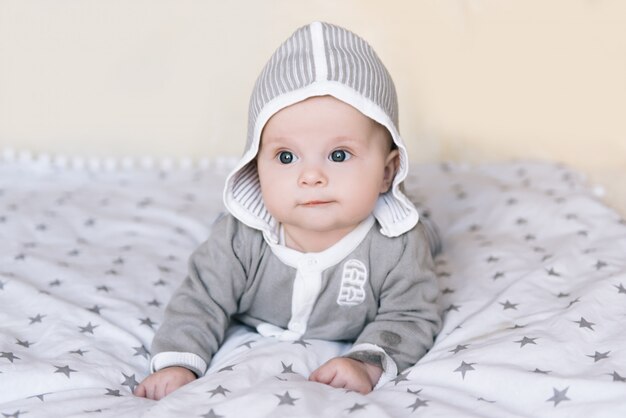 Small baby boy lying on stomach and raising his head awhile looking surprised and smiling cute, newborn