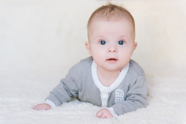 Small baby boy lying on stomach and raising his head awhile looking surprised and smiling cute, newborn