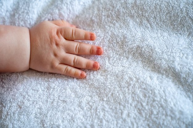 A small baby hand on white sheet