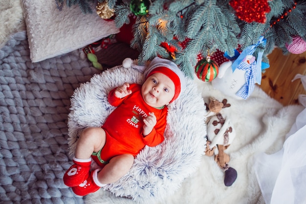 The small baby lies near Christmas Tree 