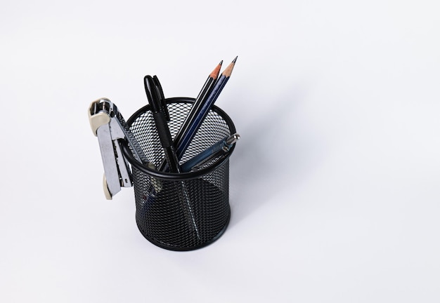 A small black basket made of round steel Can be used to store office supplies including pens pencils stapler and still have space to put more things In the white background there is copy space