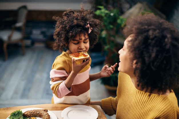 Small black girl eating toasted bread with jam for breakfast